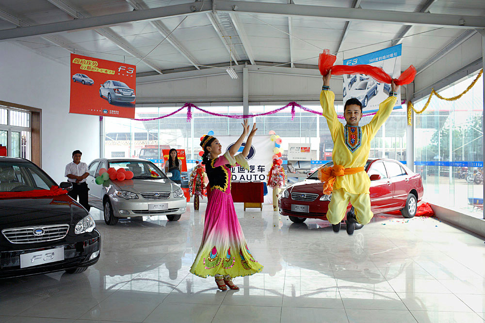 A couple performs a traditional dance in a car dealership outside Turpan, China, 2007. BYD, a new Chinese/Japanese family car was introduced for the first time in the city. 