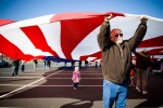 Volunteers salute veterans by unfurling a giant American flag at a flag appreciation ceremony.