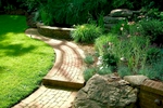 Meandering custom graduated brick walkways lead into an sanctuary filled with fragrance and aesthetics. Hardscapes harmonize alongside softscapes and there is even a custom water feature and outdoor lighting to enhance the senses.