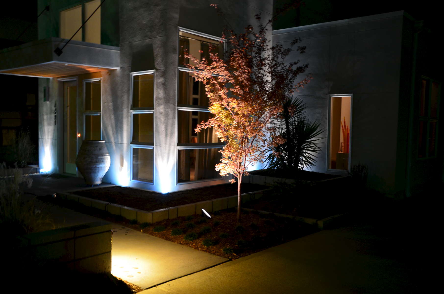 This evening image taken of this contemporary home and landscape in Cotswold shows the magical union of professional landscape design and lighting. Lighting brings the colors, textures and dimension to life after dark for all-hour enjoyment!