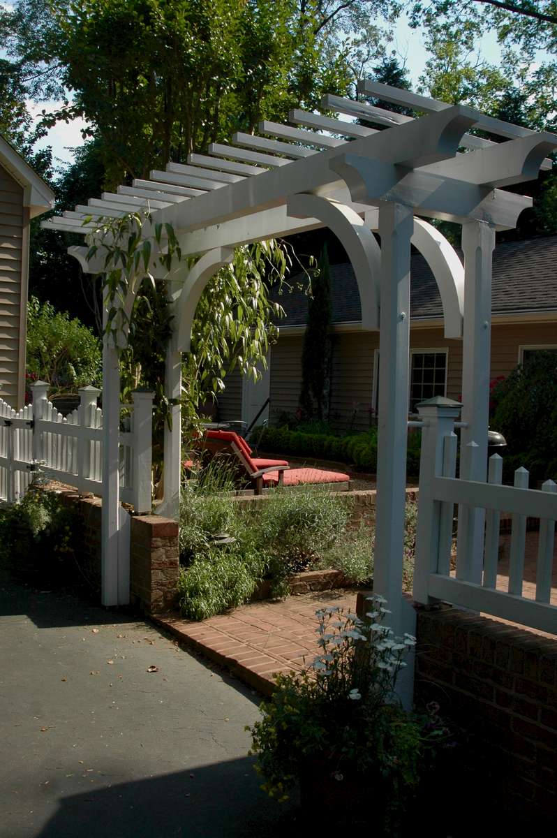 A custom pergola and picket fence seperates the driveway from an intermediate courtyard leading to the back garden.