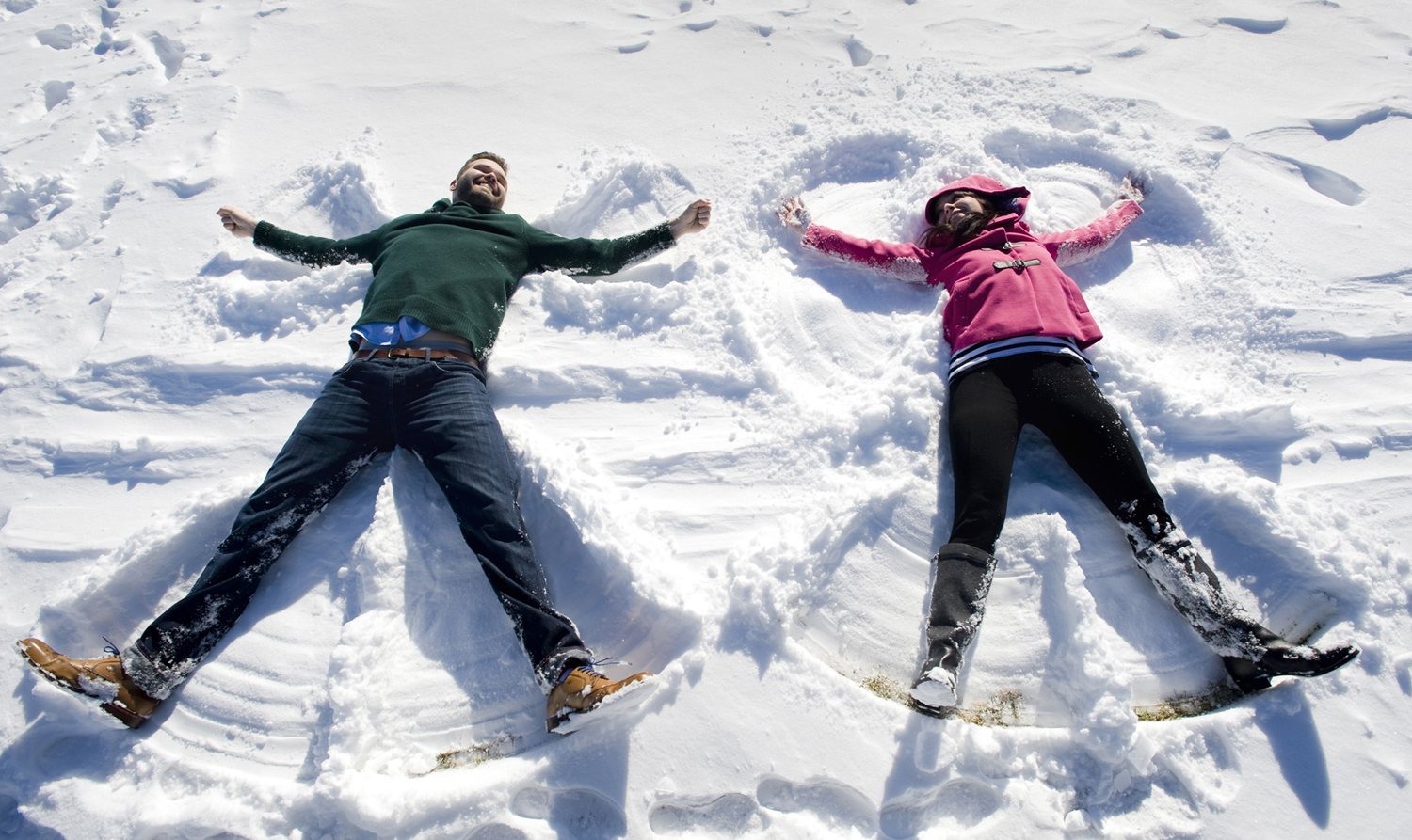engaged couple making snow angels during their snowy Hoboken engagement session. Hoboken wedding photographers