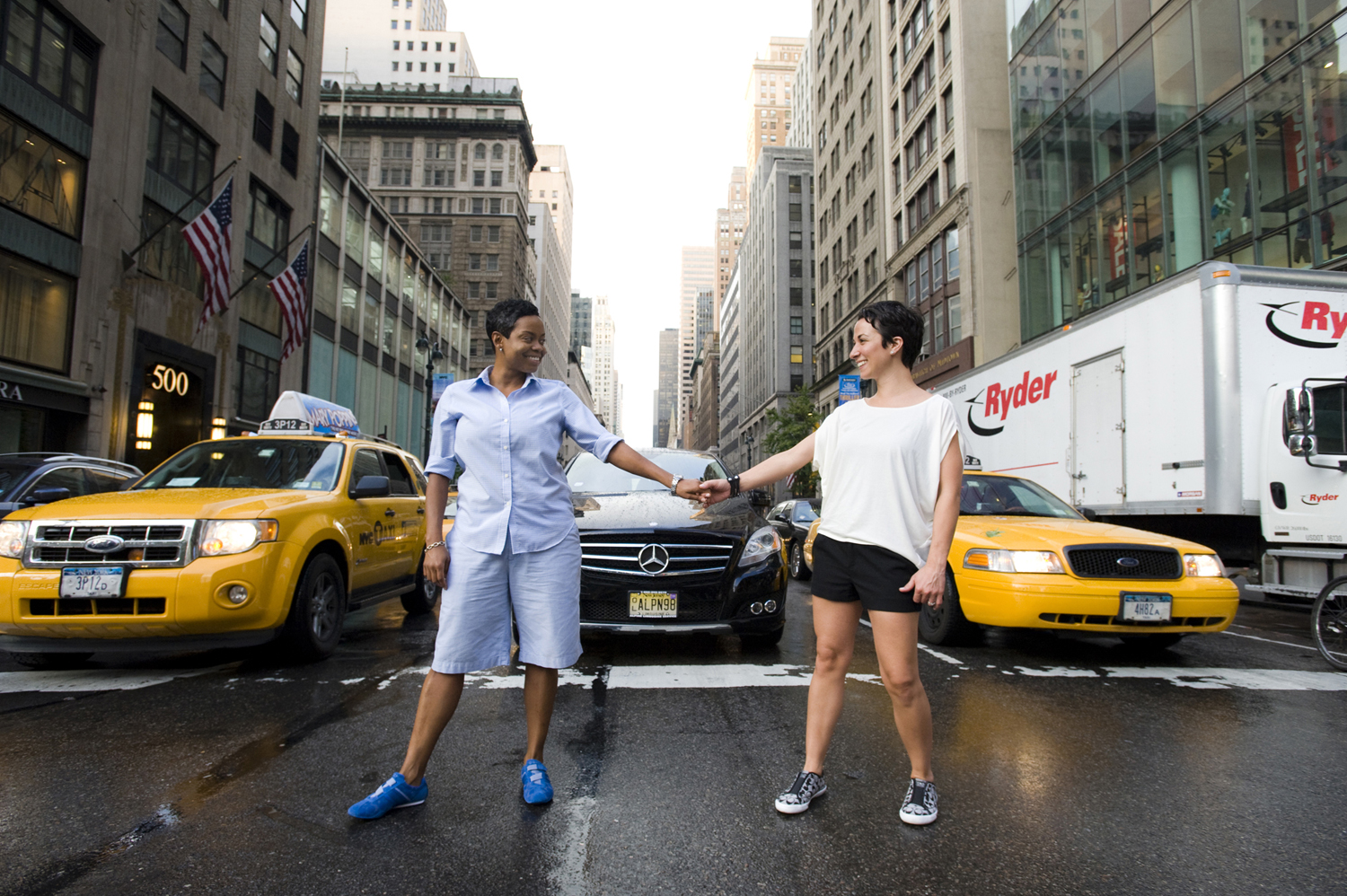 Couple standing in NYC street against yellow cabs for engagement photos. Gay-friendly NYC wedding photographers