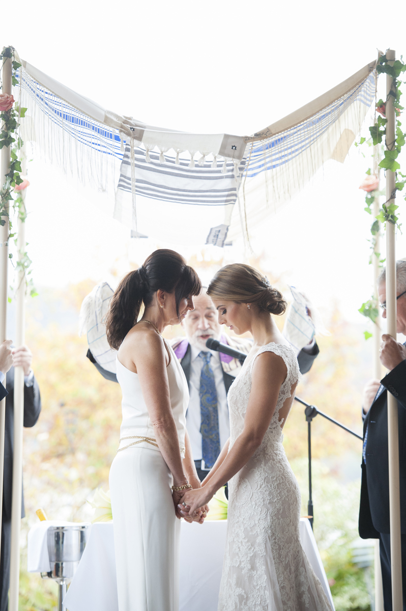 Brides under the chuppah at a Jewish wedding ceremony. NYC wedding photos