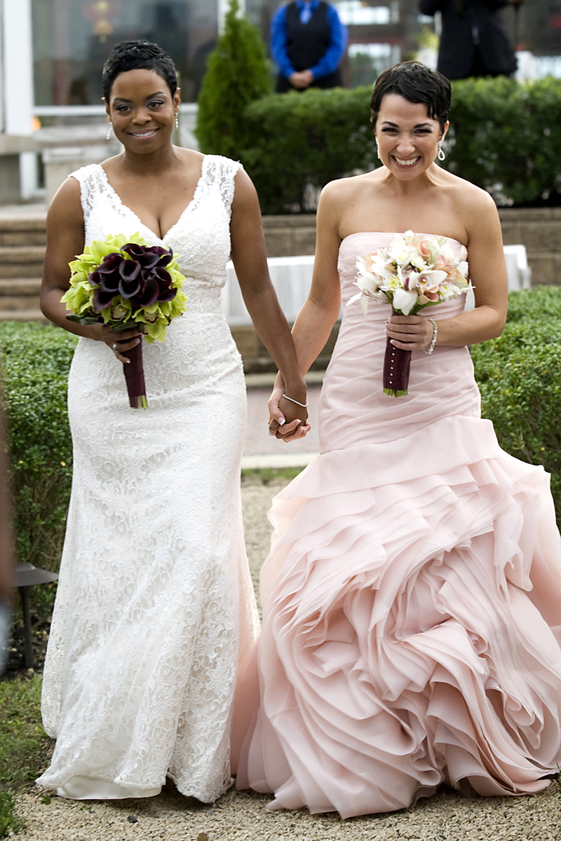Brides walk down the aisle at the start of their wedding ceremony at Liberty House. NYC gay-friendly wedding photographers