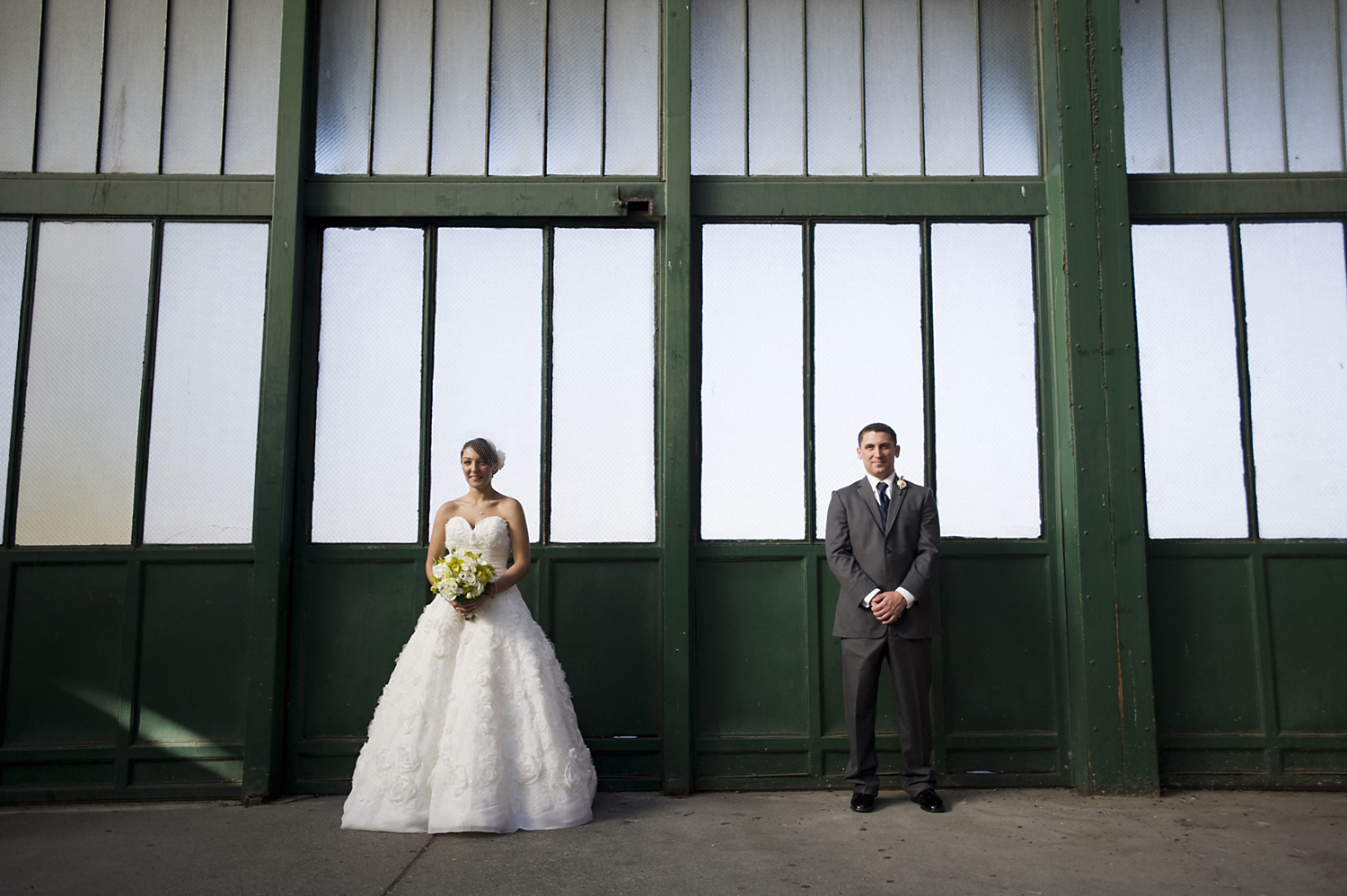 Bride and groom posing at train station in Liberty State Park before their wedding at Liberty House. 