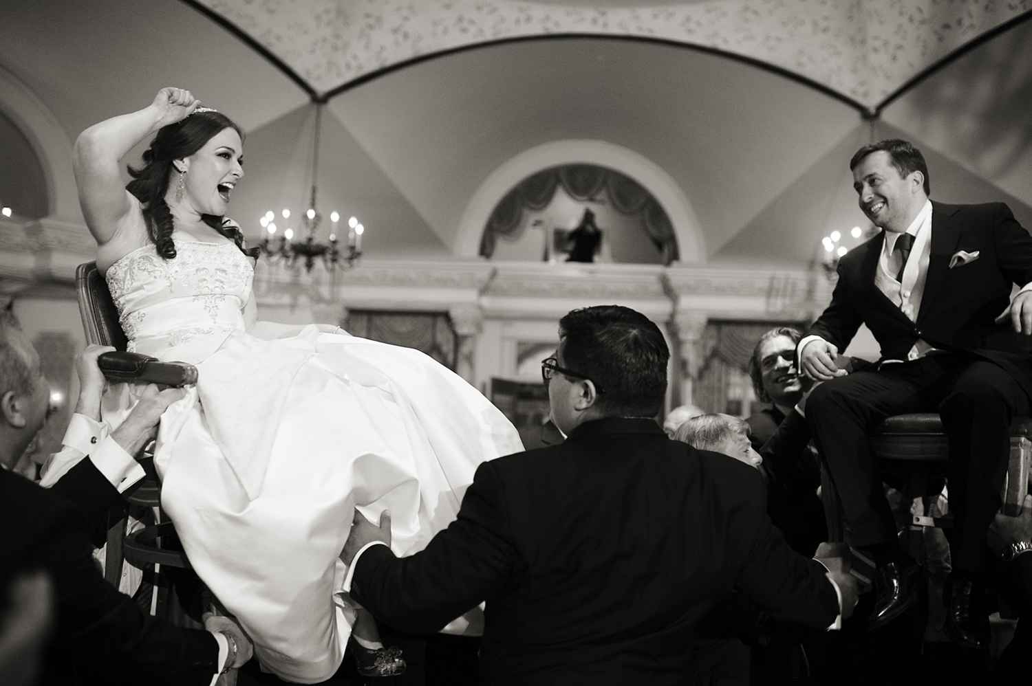 Bride and groom raised in chairs during traditional jewish dance, hora, at Pleasantdale Chateau. NJ wedding photographers