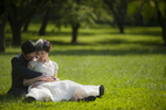 Bride and groom sitting in grass at Queens Botanical Garden after their beautiful summer wedding. NYC wedding photos