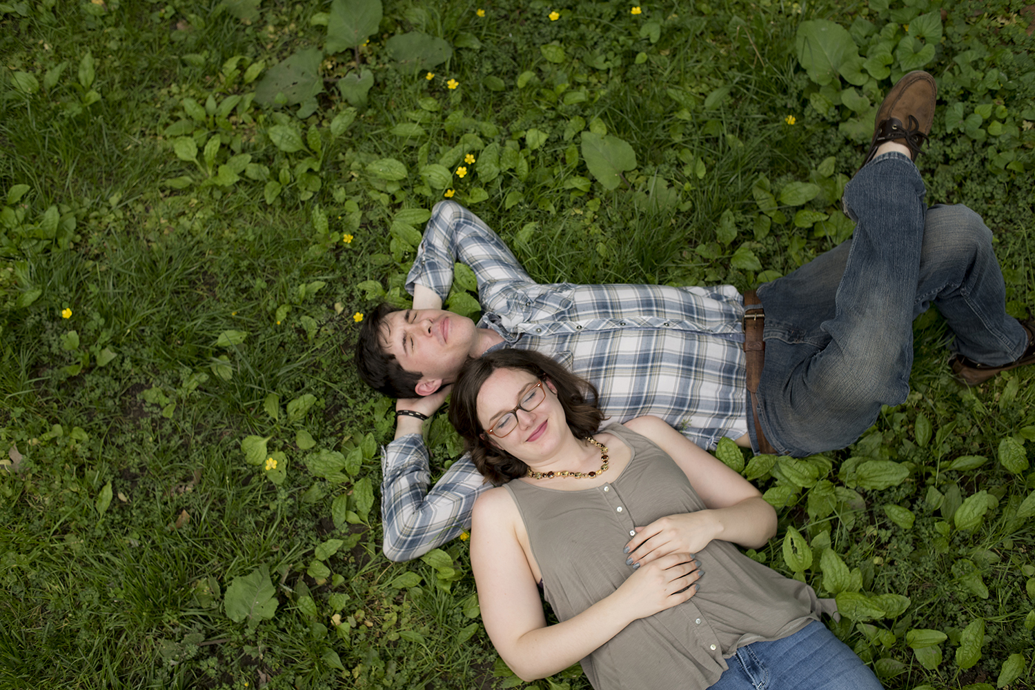 Engaged couple laying on the grass during their engagment session in Central Park