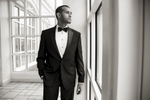 dapper groom staring out the window on wedding day at Hilton Pearl River
