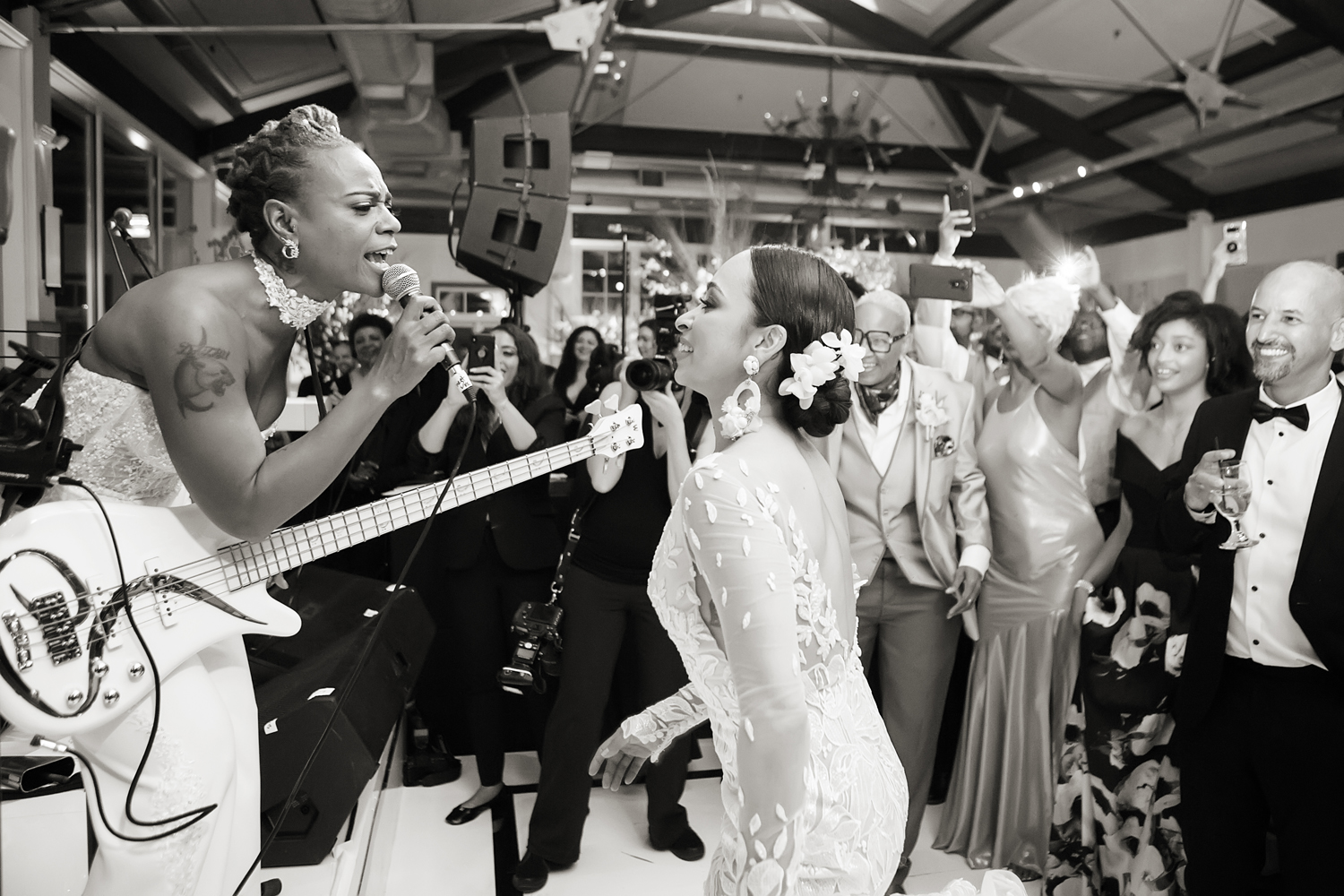bride surprises her wife with a musical performance during their wedding reception at Liberty House in Jersey City