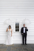 Portrait of bride and groom at Ryland Inn with umbrellas on their rainy wedding day. 