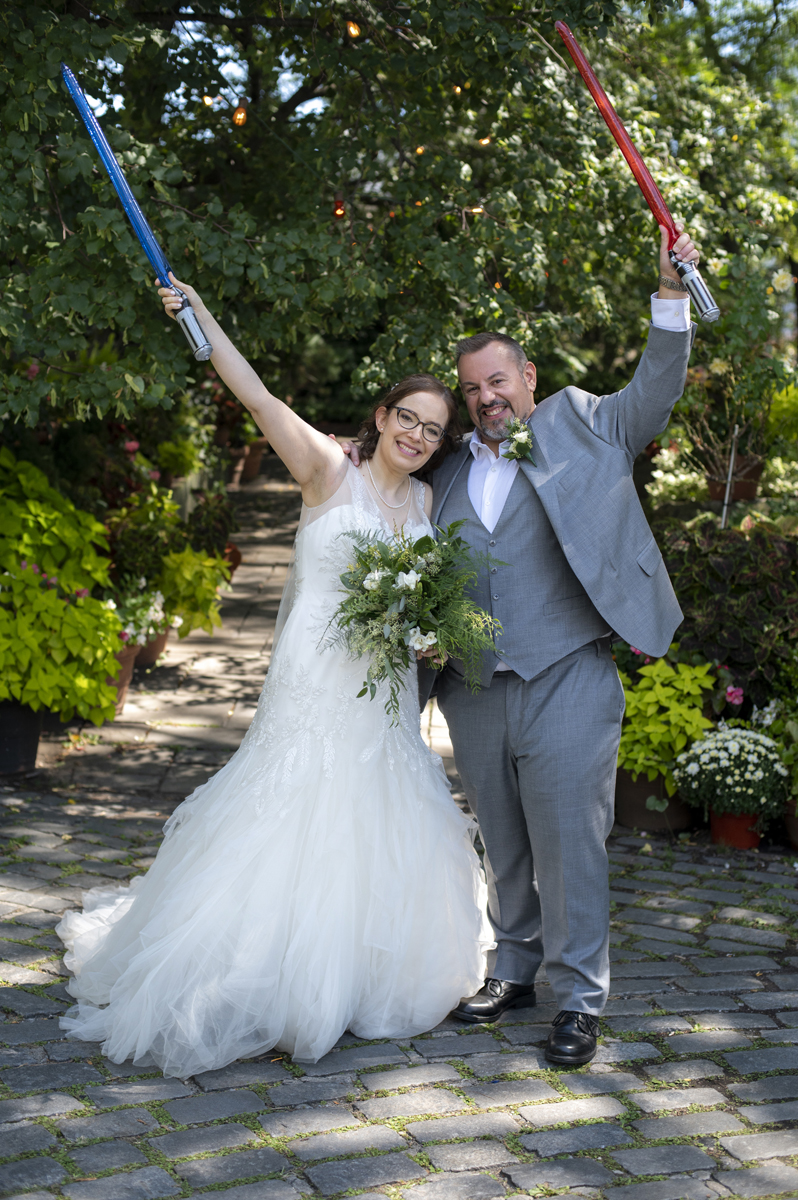 Bride and groom with Light Sabers at their wedding at The River Cafe in Brooklyn