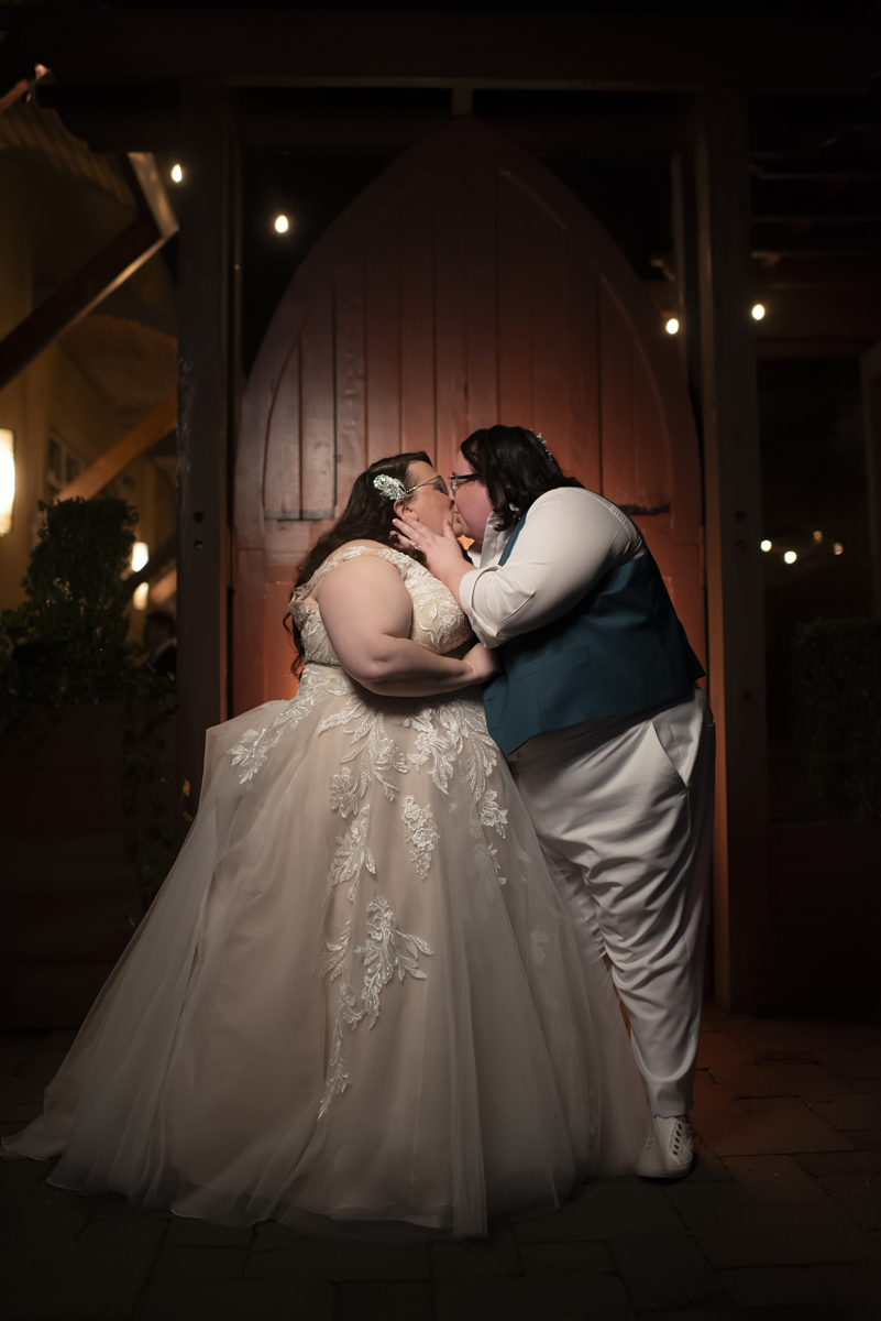 two bride kissing in front of red doors at Stone House at Stirling Ridge
