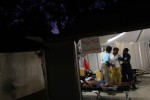 Medical staff eased an injured woman toward a cot as night descended. The Gheskio Field Hospital began to take overflow patients from the hopelessly overrun city hospital several blocks away. 
