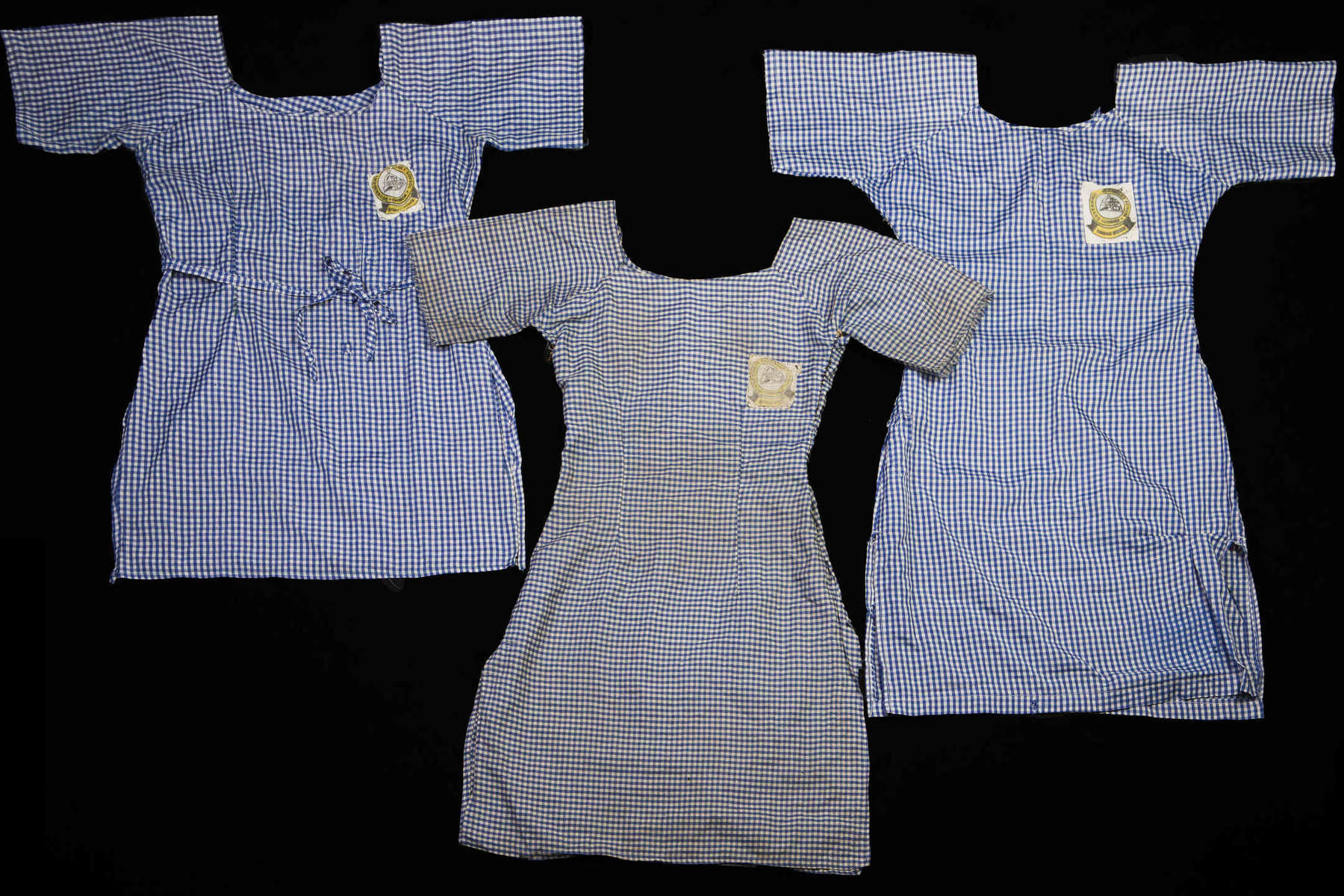Chibok girl's school uniforms. One was clearly made in a hurry, in messy stitching and different color threads. Another one was well made but utilitarian – probably stitched by the girl’s mother. Another dress was especially dirty and threadbare.  Maybe the girl was going to wash it tomorrow. Maybe she couldn’t afford soap and was waiting until she could. It’d been stitched again and again at the sides – torn and repaired, probably the only uniform she had. 