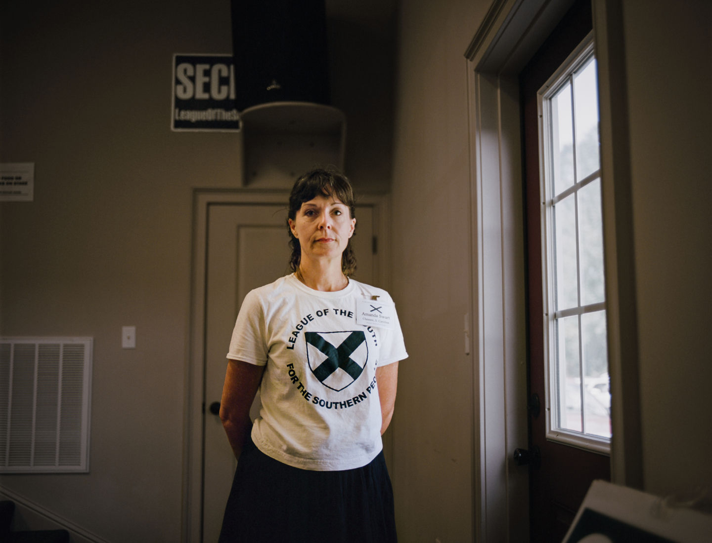 Amanda, the {quote}den mother{quote} of the League of the South, a neo-confederate group that publicly advocates for southern succession, and privately endorses slavery. This portrait was made at their annual convention in Wetumpka, Alabama on June 30, 2017. The League of the South takes great pains to distance itself and differentiate from the KKK, yet promotes many of the exact same ideas under a different outward facing rhetorical stance. The argument about “optics” pits different hate groups against each other as they vie for local power. LOS is almost completely male in its power structure and women like Amanda can only play informal roles. Amanda is not from the south but when she met her now husband online as his nutritionist and moved to Mississippi to be with him, she joined. She said that all the people at the meeting (which did include Klan members) were the greatest people she’d ever met. This reporter was forcefully ejected and escorted out of the meeting without clear cause. 