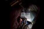 A woman reads a Hausa romance novel using the flashlight on her cell phone as the train chugged along slowly through the night. 