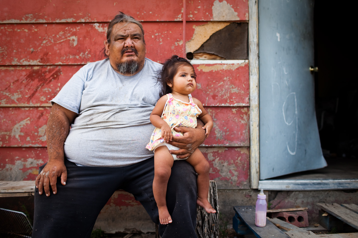 George Eagle Bull sits with his niece, Kimimilia, in front of his house in Pine Ridge, South Dakota, on Friday, July 24, 2009. 