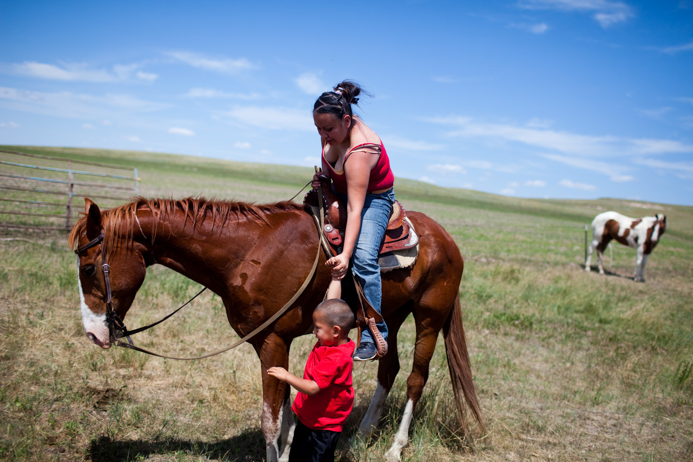 A young mother helps her son onto the horse on Pine Ridge Reservation, South Dakota.  Family values are something that elders in the community see as being lost among the younger generations as they turn to drugs, alcohol, and gang activity.