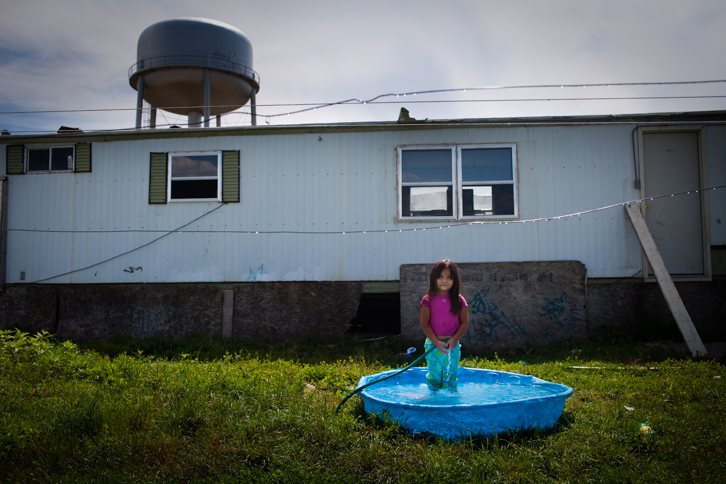 A young girl stands in front of her trailor in Pine Ridge, South Dakota.  Pine Ridge Reservation, located in Shannon County, is considered the poorest county in the United States.  Gang violence, unemployment, and alcoholism are major problems throughout the reservation. 
