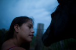 Alexis Oxendine pets one of the horses on Pine Ridge Reservation.  Many people use horses a primary means of transportation during the summer to get from place to place. 