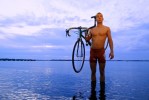 Triathlete Andre Fosta poses for a portrait with his bicycle while standing in Lake Minneola.