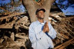 Katrina survivor Robert Green says a prayer in front of the debris of what used to be his house in the lower 9th Ward. Green said that his house hit against the large oak tree when it floated off of its foundation during the storm. In the process of evacuating his family from the house to the more stable tree he lost the grip of his mother and granddaughter who were swept away in the storm water and died.
