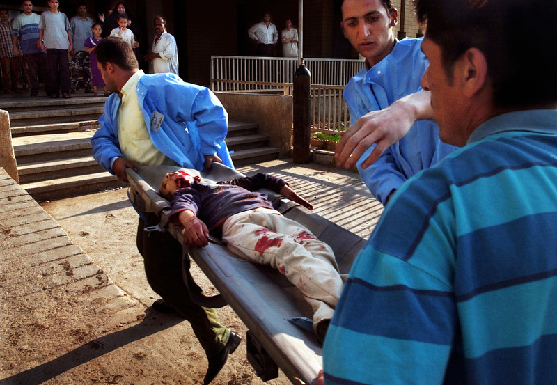 A young girl is rushed into the emergency room by hospital workers at Saddam Children's Park Nurse Villa Hospital in Baghdad, Iraq She was pronounced dead on arrival. She and her brother were playing with an unexploded cluster bomb that detonated, killing both of them. During the initial invasion by U.S. troops, Iraq experienced a public health crisis as war victims flooded hospitals and clinics. (Chris Schneider/EW Scripps) 