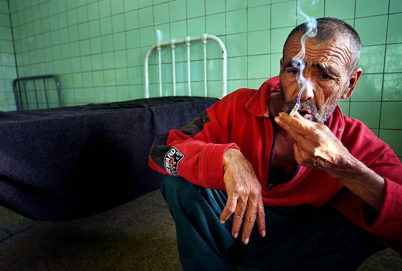 A patient smokes in his room at Rashad psychiatric hospital. The patients have little to do and spend their days sleeping and smoking cigarettes.