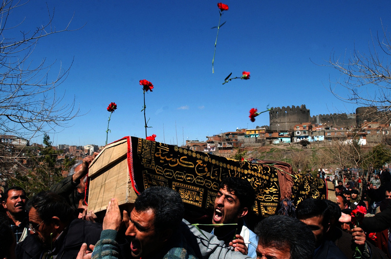 Mourners toss flowers onto the casket of Burhan Karadeniz as it is carried into a cemetery in Diyarbakir, Turkey. Karadeniz was a Kurdish journalist who died in exile and was brought home to be buried. His funeral was a flashpoint of Kurdish and Turkish tensions and was closely monitored by the Turkish police. (Photo by Chris Schneider)