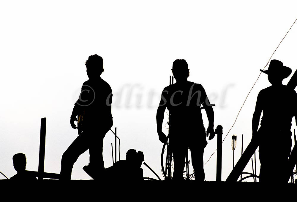 Mexican laborers on a construction site in Zihuantenejo Mexico are sihouetted against a clear white sky. To purchase this image, please go to my stock agency click here.