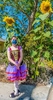 A ballerina in costume stands outside by a large sunflower during the COVID-19 pandemic.