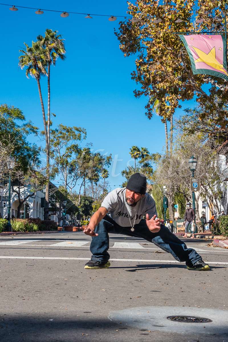 A hispanic man doing tai chi in the middle of State Street in Santa Barbara, California.