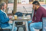 Two card players playing outside in the Paseo Nuevo Mall in Santa Barbara, California during the COVID pandemic. One of the two wears a face mask.