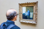 Man in blue looking at Vermeer painting of {quote}Woman in Blue Reading a Letter{quote} in an art gallery.