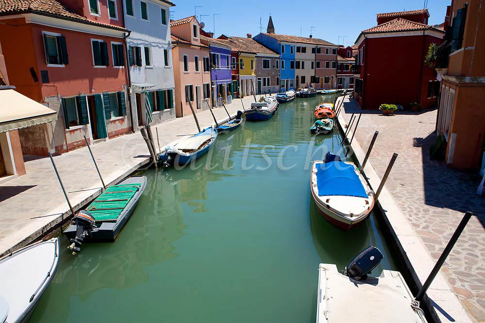 A canal is lined with small boats and colorful houses on the Italian island of Burano off the coast of Venice, Italy. To purchase this image, please go to my stock agency click here.