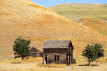 Abandoned farm buildings sit against dry golden hills in the Central Valley of California. To purchase this image, please go to my stock agency click here.