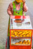 A middle-aged female street vendor pushes her wheeled cart selling embanadas in Cochabamba, Bolivia.