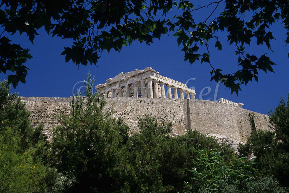 A distant view framed by trees and shrubbery of the Parthenon located on the Acropolis. To purchase this image, please go to my stock agency click here.