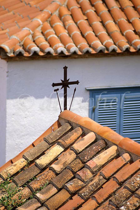 A detail of a Greek church showing tile roof  and cross on the island of Hydra, one of the Saronic Islands, located in the Aegean Sea between the Saronic Gulf and the Argolic Gulf. To purchase this image, please go to my stock agency click here.
