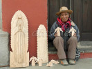 A seasoned wood carver making wooden statues for sale to tourists sits in a doorway in the early hours of the morning.