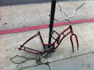 Red bicycle missing wheels, seat and other parts chained to pole in downtown Santa Barbara, CA 