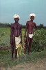 Two turbaned field workers wearing loin cloths and carrying machetes stand by their field in the southern India state of Tamil Nadu. To purchase this image, please go to my stock agency click here.