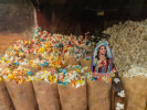 Printed paper Jesus in bag of colored popcorn along with other bags of colored popcorn in a popcorn vendor's cart along a street in Capiata, Paraguay.