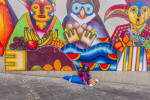 Woman seated by colorful mural, La Paz, Bolivia.