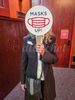 An user at the Ensemble Theater in Santa Barbara holds up a sign requiring masks to be worn at the event.