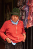 An indigenous female store owner stands in the doorway of her store across from the central market in Octovalo, Ecuador. She is dressed traditional clothing including a {quote}fedora{quote} type hat, worn by women of the region. She is looking to the side.