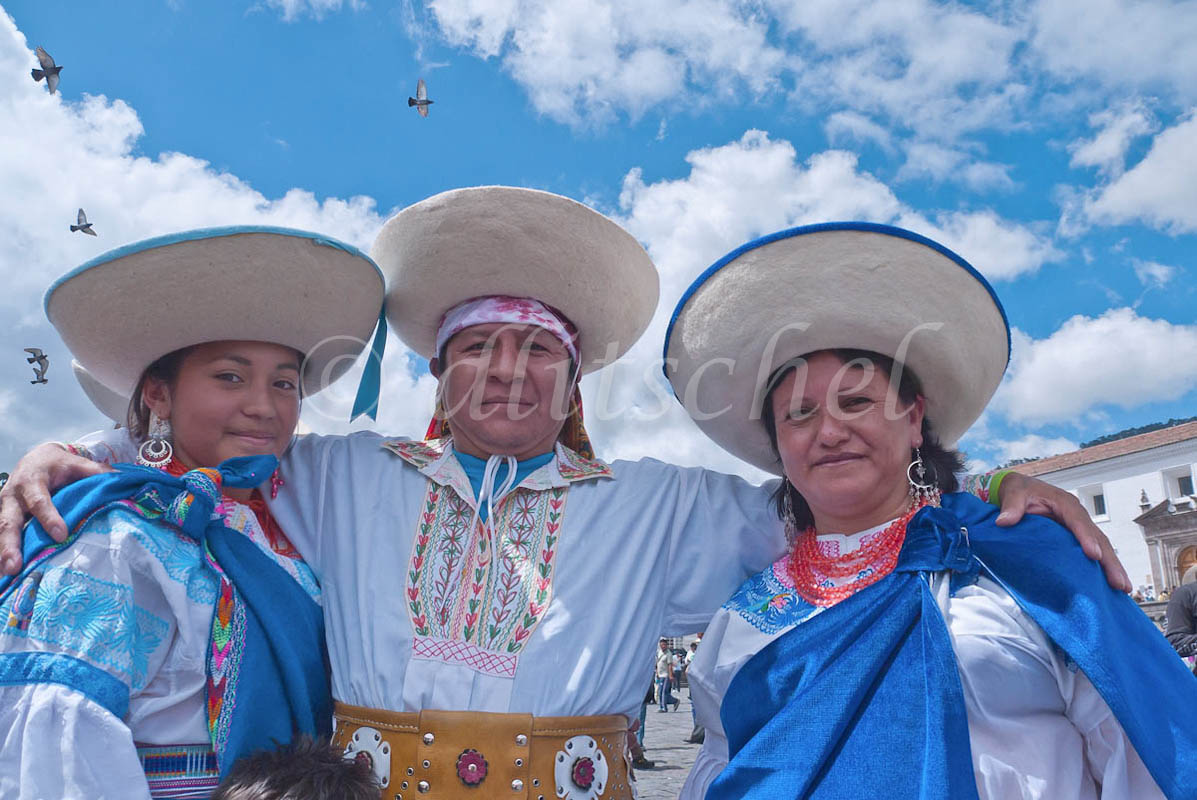 Three Hispanic dancers, two women and a man, from a folklorico group in Quito, Ecuador pose after performing a traditional dance in the San Francisco Plaza. All three are wearing sombreros and customary clothing.