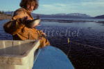 Russian fisherman on lake in Northern Siberia throwing caught fish into cooler on boat. To purchase this image, please go to my stock agency click here.